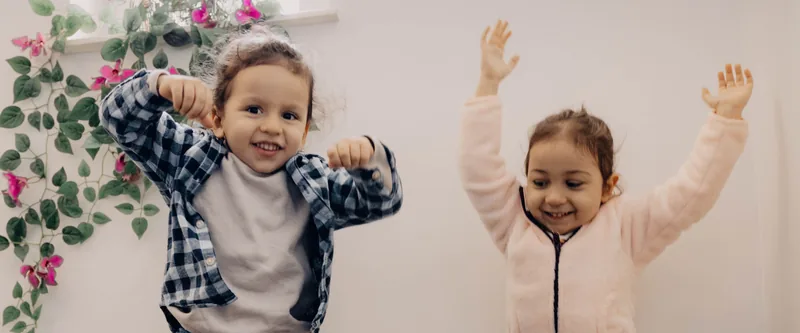 Two children jumping with their arms in the air